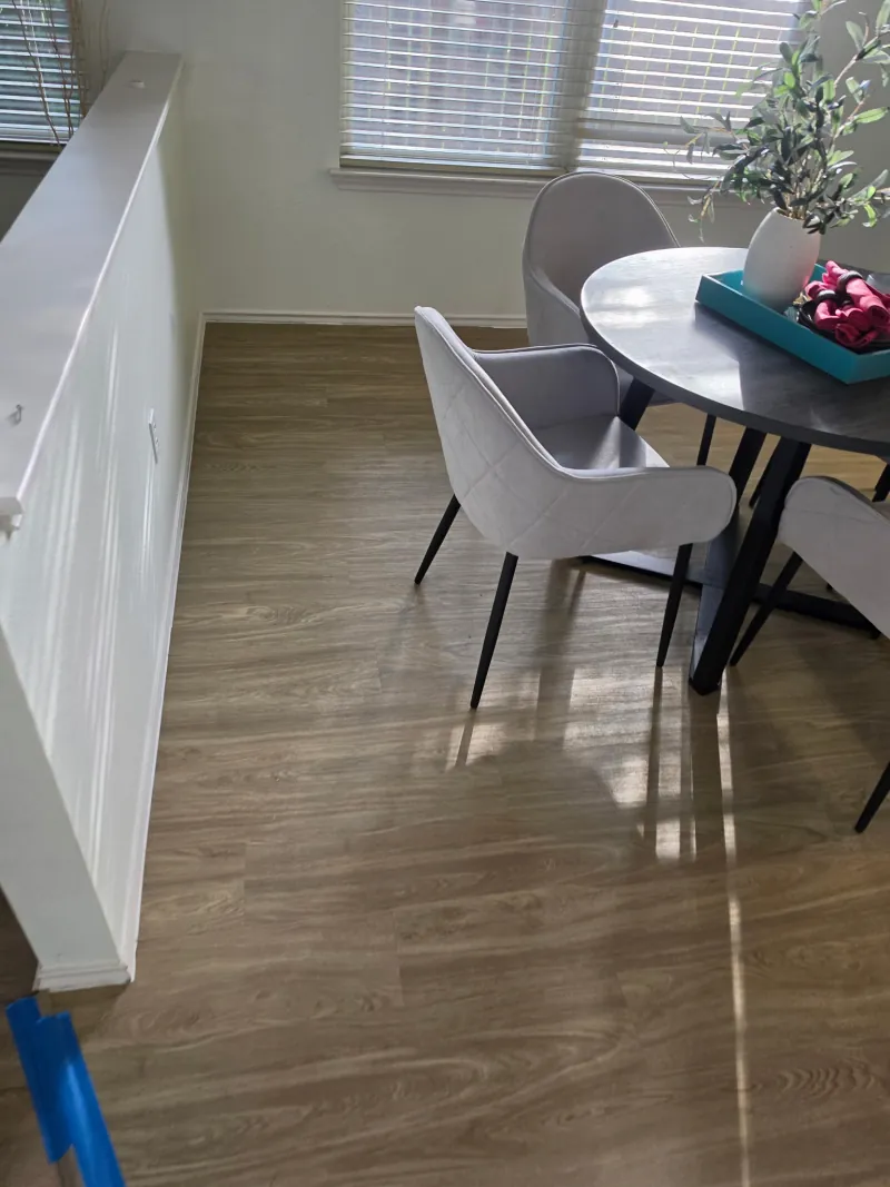 Comedor con mesa redonda y sillas grises sobre piso SPC roble claro instalado por Pisos Potosinos